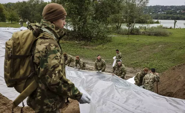 Soldiers build barriers with sandbags against flood water at the bank of Danube River in Pilismarot, Hungary, Monday, Sept. 16, 2024. (Robert Hegedus/MTI via AP)