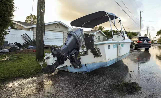 A boat rests on a street after being relocated during flooding caused by Hurricane Helene Friday, Sept. 27, 2024, in Hudson, Fla. (AP Photo/Mike Carlson)