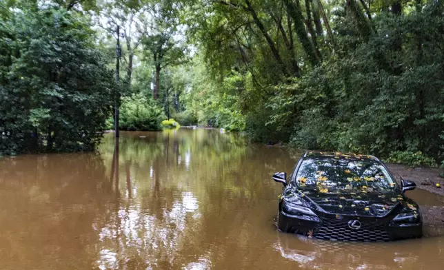 A partially submerged vehicle sits in flood water from after Hurricane Helene passed the area, Friday, Sept 27, 2024, in Atlanta. (AP Photo/Jason Allen)