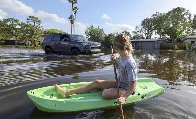 Halle Brooks kayaks down a street flooded by Hurricane Helene in the Shore Acres neighborhood Friday, Sept. 27, 2024, in St. Petersburg, Fla. (AP Photo/Mike Carlson)