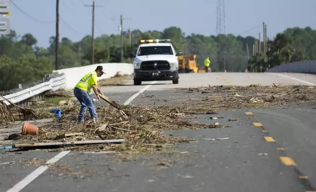 Workers remove debris in the aftermath of Hurricane Helene, in Cedar Key, Fla., Friday, Sept. 27, 2024. (AP Photo/Gerald Herbert)