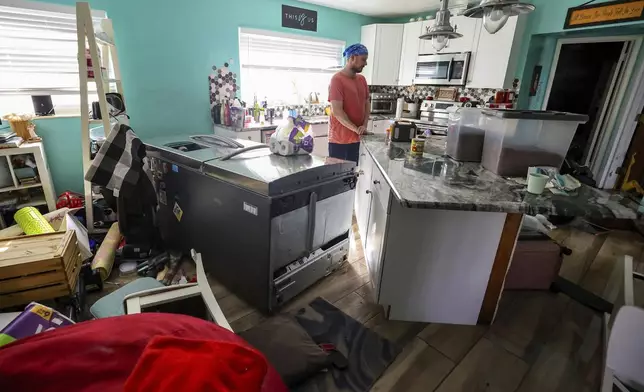 Bradley Tennant looks through his house flooded with water from Hurricane Helene in the Shore Acres neighborhood Friday, Sept. 27, 2024, in St. Petersburg, Fla. (AP Photo/Mike Carlson)