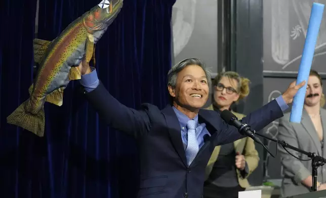 Professor James Liao displays a stuffed fish while accepting a prize for physics for demonstrating and explaining the swimming abilities of a dead trout during a performance at the Ig Nobel Prize ceremony at Massachusetts Institute of Technology in Cambridge, Mass., Thursday, Sept. 12, 2024. (AP Photo/Steven Senne)