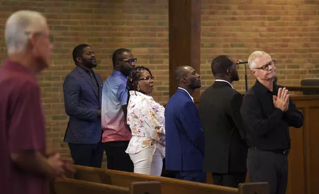 Members of the Haitian community, from left, Lindsay Aime, James Fleurijean, Rose-Thamar Joseph, Harold Herard, and Viles Dorsainvil, stand for worship with Carl Ruby, pastor at Central Christian Church, in Springfield, Ohio, on Sunday, Sept. 15, 2024. (AP Photo/Jessie Wardarski)