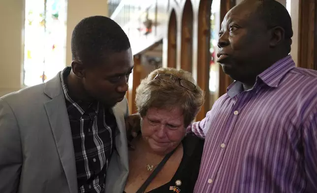 St Raphael Catholic church parishioners, Berthing Jean Philippe, left, Casey Kelly Rollins and Patrick Joseph embrace after a service in support of the Haitian in Springfield, Ohio, Sunday, Sept. 15, 2024. (AP Photo/Luis Andres Henao)