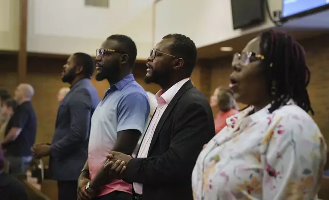 Members of the Haitian community in Springfield, Ohio, from left, Lindsay Aime, James Fleurijean, Viles Dorsainvil, and Rose-Thamar Joseph, stand for worship at Central Christian Church, on Sunday, Sept. 15, 2024. (AP Photo/Jessie Wardarski)