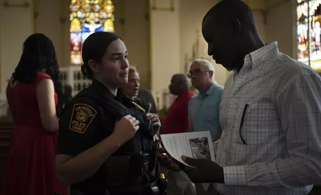 A Springfield police officer talks to a parishioner after a service in support of the Haitian community at St. Raphael Catholic church in Springfield, Ohio, Sunday, Sept. 15, 2024. (AP Photo/Luis Andres Henao)