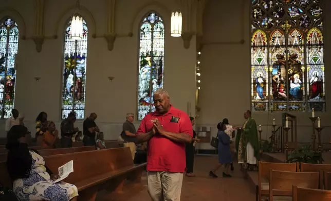 A parishioner walks back to his pew after taking Communion during a service in support of the Haitian community at St. Raphael Catholic church in Springfield, Ohio, Sunday, Sept. 15, 2024. (AP Photo/Luis Andres Henao)