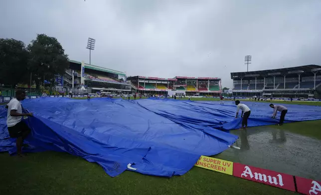 Ground personnel remove covers from the outfield before the start of the second cricket test match between Bangladesh and India at the Green Park stadium in Kanpur, India, Friday, Sept. 27, 2024. (AP Photo/Ajit Solanki)