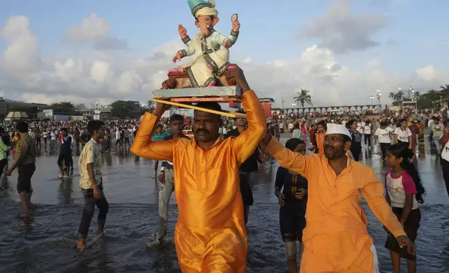 A devotee carries an idol of elephant-headed Hindu god Ganesha on his head for immersion in the Arabian Sea, during the Ganesh Chaturthi festival in Mumbai, India, Sunday, Sept. 8, 2024. (AP Photo/Rafiq Maqbool)