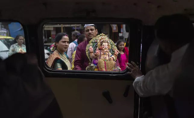 A family carries an idol of elephant-headed Hindu god Ganesha to home for worship during Ganesh Chaturthi festival celebrations in Mumbai, India, Saturday, Sept. 7, 2024. (AP Photo/Rafiq Maqbool)