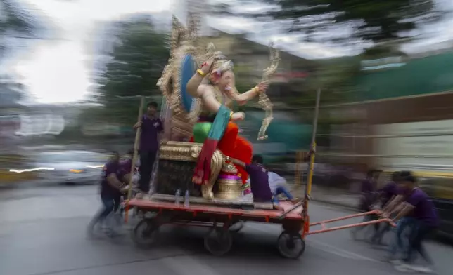 An idol of the elephant-headed Hindu god Ganesh is transported through a street to a place of worship ahead of the Ganesh Chaturti festival in Mumbai, India, Wednesday, Sept. 4, 2024. (AP Photo/Rafiq Maqbool)