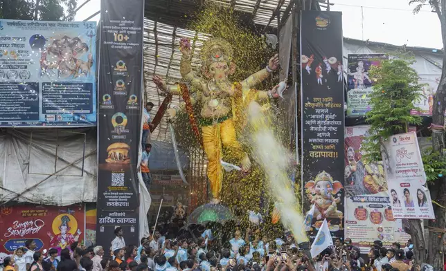 Devotees light firecrackers as an idol of the elephant-headed Hindu god Ganesh is transported to a place of worship during the Ganesh Chaturti festival in Mumbai, India, Wednesday, Sept. 4, 2024. (AP Photo/Rafiq Maqbool)