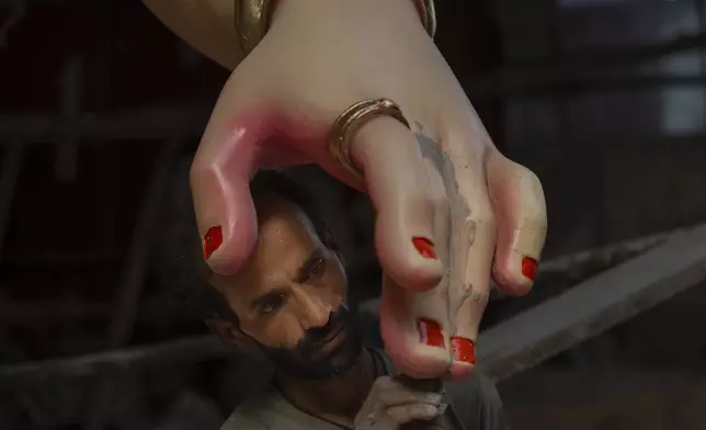 An artist works on an idol of the elephant-headed Hindu god Ganesha inside a workshop ahead of Ganesh Chaturthi festival in Mumbai, India, Wednesday, Sept. 4, 2024. (AP Photo/Rafiq Maqbool)