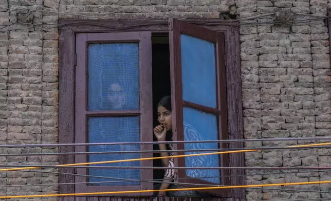 People watch from a window during a road show of Peoples Democratic Party (PDP) candidate Arif Laigroo, in Srinagar, Indian-controlled Kashmir Sunday, Sept. 15, 2024. (AP Photo/Mukhtar Khan, File)