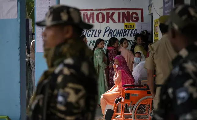 Paramilitary soldiers stand guard as people queue up to vote during the first phase of the Jammu and Kashmir assembly election, in Kishtwar, India, Wednesday, Sept. 18, 2024. (AP Photo/Channi Anand)