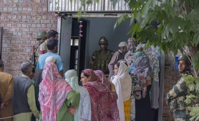 Indian paramilitary soldiers stand guard as people queue up at a polling booth to cast their vote in Naira, south of Srinagar, Indian controlled Kashmir, Wednesday, Sept. 18, 2024. (AP Photo/Dar Yasin)