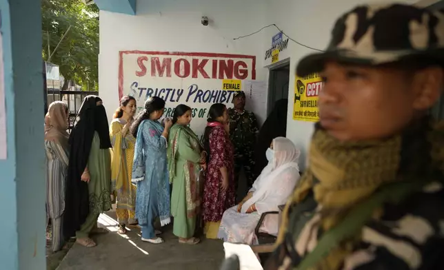 Paramilitary soldiers stand guard as people queue up to vote during the first phase of the Jammu and Kashmir assembly election, in Kishtwar, India, Wednesday, Sept. 18, 2024. (AP Photo/Channi Anand)