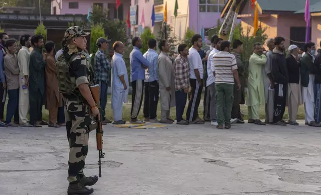 An Indian paramilitary soldier stands guard as Kashmiri's queue up at a polling booth to cast their vote during the second phase of the assembly election in the outskirts of Srinagar, Indian controlled Kashmir, Wednesday, Sept. 25, 2024. (AP Photo/Dar Yasin)