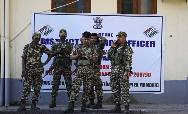 Security personnel members stand and wait as polling officials prepare to leave for their respective polling booths on the eve of the first phase of the Jammu and Kashmir Assembly election, in Ramban 150 kilometers (94 miles) northeast of Jammu, India, Tuesday, Sept. 17, 2024. (AP Photo/Channi Anand)