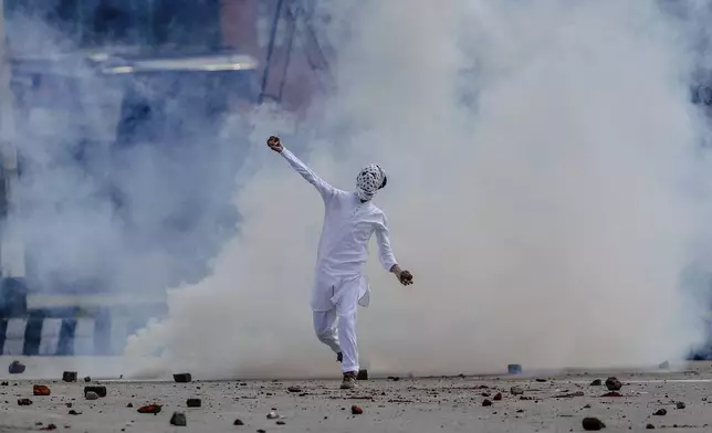 A masked protester throws stone at Indian security forces during a protest after Eid prayers in Srinagar, Indian controlled Kashmir, Saturday, June 16, 2018. (AP Photo/Dar Yasin, File)