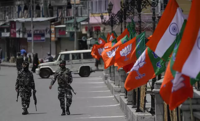 Indian security forces walk past Indian flags and flags of India's ruling Bharatiya Janata Party (BJP) as a motorcycle rally by BJP youth wing to the Kargil War Memorial passes through Srinagar, Indian controlled Kashmir, Monday, July 25, 2022. (AP Photo/Mukhtar Khan, File)