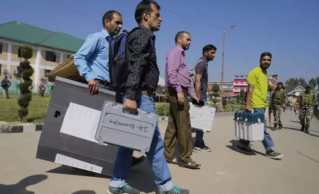 Polling officials carry electronic voting machines and other election material to a venue for distribution, in Pulwama south of Srinagar, Indian controlled Kashmir, Tuesday, Sept. 17, 2024. (AP Photo/Mukhtar Khan)