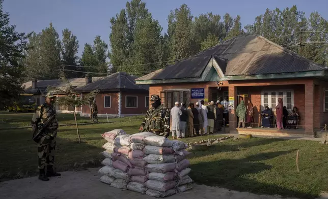 Indian paramilitary soldiers stand guard as Kashmiri's queue up at a polling booth to cast their vote in Marval, south of Srinagar, Indian controlled Kashmir, Wednesday, Sept. 18, 2024. (AP Photo/Dar Yasin)