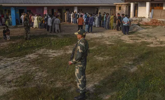 An Indian paramilitary soldier stands guard as Kashmiri's queue up at a polling booth to cast their vote during the second phase of the assembly election in the outskirts of Srinagar, Indian controlled Kashmir, Wednesday, Sept. 25, 2024. (AP Photo/Dar Yasin)