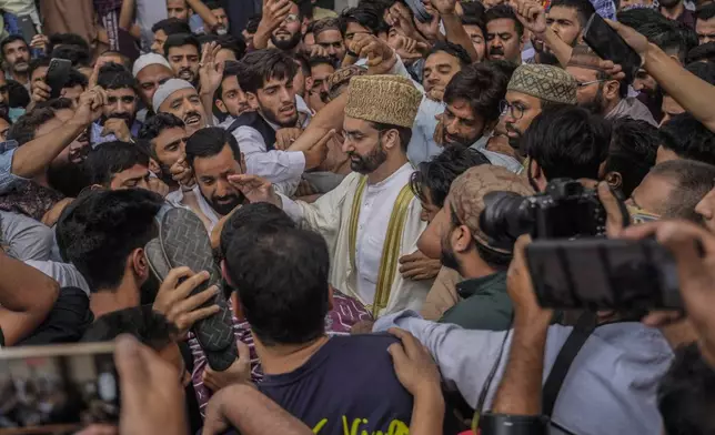 FILE- Supporters assemble to welcome top Kashmiri separatist leader Mirwaiz Umar Farooq, center, as he arrives to offer Friday prayers outside the Jamia Masjid or Grand Mosque in Srinagar, Indian controlled Kashmir, Sept. 22, 2023. (AP Photo/Mukhtar Khan, File)