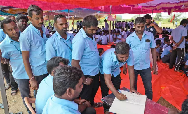 Samsung workers who are on strike sign a register as they arrive for a protest near their plant in Sriperumbudur, on the outskirts of Chennai, India, Tuesday, Sept. 24, 2024. (AP Photo/Mahesh Kumar A.)