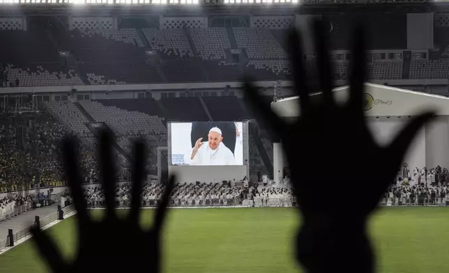 Catholic faithful attend a holy mass led by Pope Francis, shown on the screen, at the Gelora Bung Karno Stadium, in Jakarta, Thursday, Sept. 5, 2024. (Yasuyoshi Chiba/Pool Photo via AP)