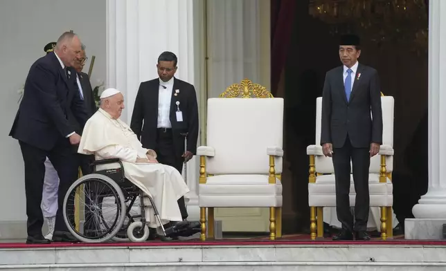 Indonesian President Joko Widodo, right, receives Pope Francis, helped on a wheelchair by assistant Piergiorgio Zanetti, at Istana Merdeka Presidential Palace in Jakarta, Wednesday, Sept. 4, 2024. Pope Francis is opening his visit to Indonesia with a packed first day Wednesday, meeting political and religious leaders and setting a rigorous pace for an 11-day, four-nation trip through tropical Asia and Oceania that will test his stamina and health. (AP Photo/Gregorio Borgia)