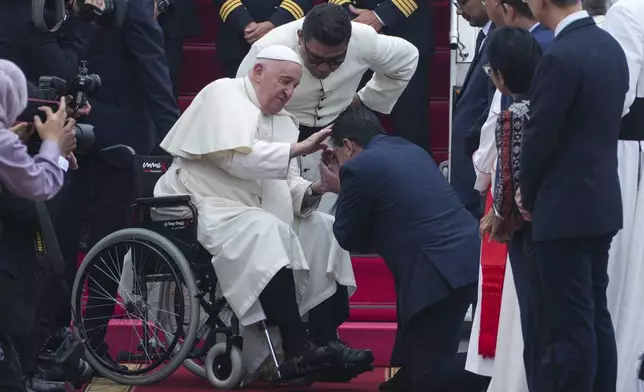 Pope Francis, left, is greeted by an Indonesian official upon his arrival at Soekarno-Hatta International Airport in Tangerang, Indonesia, Tuesday, Sept. 3, 2024. (AP Photo/Achmad Ibrahim)