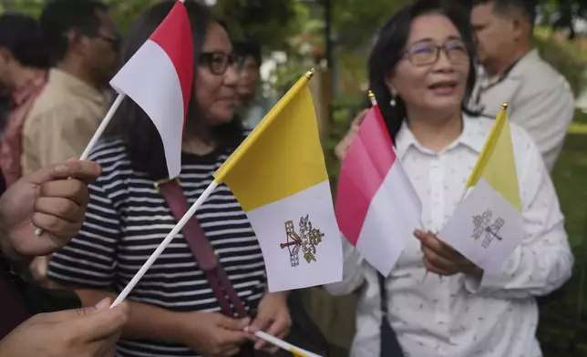 People hold Indonesian and Vatican flags as they welcome the arrival of Pope Francis outside the Vatican Embassy in Jakarta, Indonesia, Tuesday, Sept. 3, 2024. (AP Photo/Dita Alangkara)