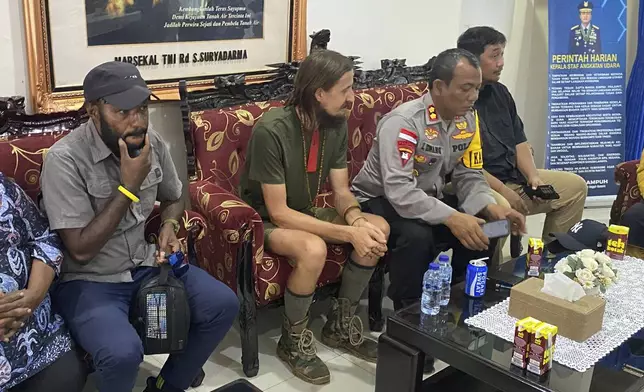 In this photo released by Cartenz Peace Task Force (Satgas Damai Cartenz) of the Indonesian security forces, New Zealand pilot Phillip Mehrtens, left, who was held hostage for more than a year in the restive Papua region, sits with police officers after his release, in Timika, Papua province, Saturday, Sept. 21, 2024. (Satgas Damai Cartenz via AP)