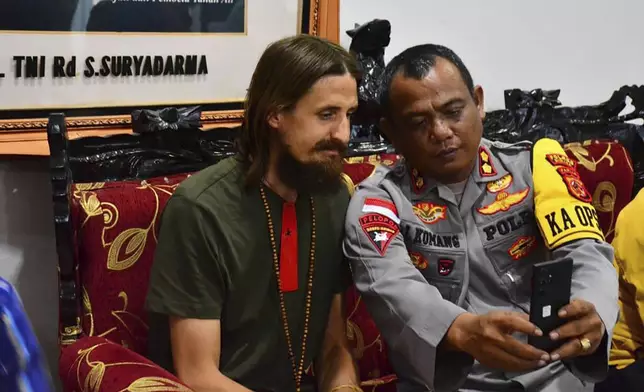 In this photo released by Cartenz Peace Task Force (Satgas Damai Cartenz) of the Indonesian security forces, New Zealand pilot Phillip Mehrtens, left, who was held hostage for more than a year in the restive Papua region, sits with a police officers after his release, in Timika, Papua province, Saturday, Sept. 21, 2024. (Satgas Damai Cartenz via AP)