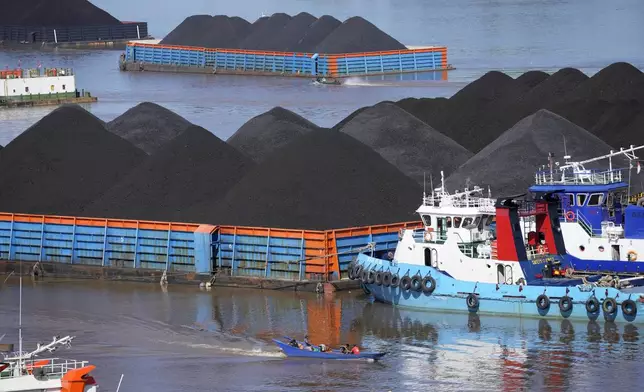 FILE- Boats cruise near barges fully loaded with coal on the Mahakam river in Samarinda, East Kalimantan, Indonesia, on Dec. 19, 2022. (AP Photo/Dita Alangkara, File)