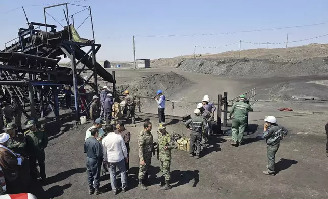 In this photo released by Iranian Red Crescent Society, miners and police officers gather around the site of a coal mine where methane leak sparked an explosion on Saturday, in Tabas, some 335 miles (540 kilometers) southeast of the capital Tehran, Iran, Sunday, Sept. 22, 2024. (Iranian Red Crescent Society, via AP)