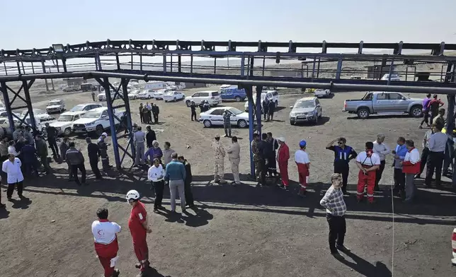 In this photo released by Iranian Red Crescent Society, rescue personnel, police officers and some other people gather around the site of a coal mine where methane leak sparked an explosion on Saturday, in Tabas, some 335 miles (540 kilometers) southeast of the capital Tehran, Iran, Sunday, Sept. 22, 2024. (Iranian Red Crescent Society, via AP)