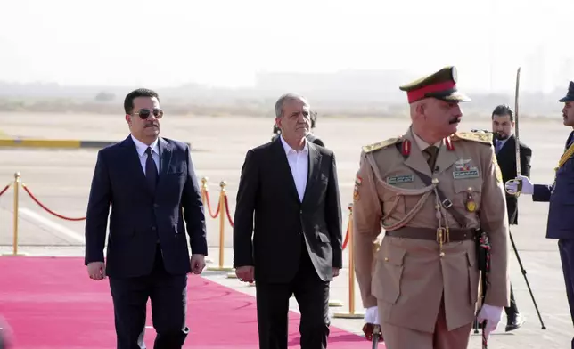 Iranian President Masoud Pezeshkian is welcomed by Iraqi Prime Minister Mohammed Shia al-Sudani, left, with an official ceremony at the Baghdad International Airport in Baghdad, Iraq, Wednesday Sept. 11, 2024. (Murtadha Al-Sudani/Pool Photo via AP)