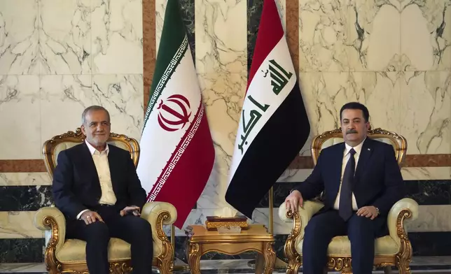 Iranian President Masoud Pezeshkian, left, is welcomed by Iraqi Prime Minister Mohammed Shia al-Sudani, right, in Baghdad, Iraq, Wednesday Sept. 11, 2024. (Murtadha Al-Sudani/Pool Photo via AP)