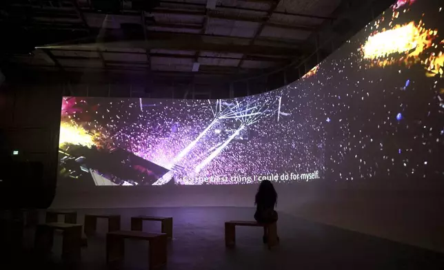 A woman watches a video of the Nova Music Festival after the Oct. 7, 2023, attack by Hamas, at an exhibition after a vigil Sunday, Sept. 1, 2024, in Culver City, Calif., for the six hostages who were found dead in Rafah, southern Gaza. (AP Photo/Ryan Sun)