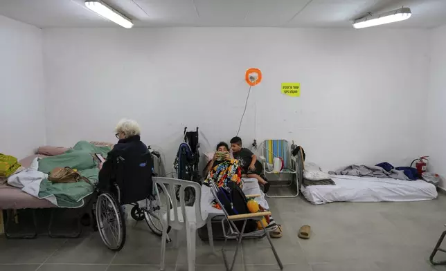 Israelis rest in a residential building bomb shelter to stay safe from rockets fired from Lebanon, in Kiryat Haim, northern Israel, on Tuesday, Sept. 24, 2024. (AP Photo/Baz Ratner)