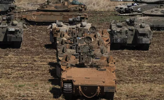 Israeli soldiers work on tanks and APC in northern Israel on Friday, Sept. 27, 2024. (AP Photo/Baz Ratner)