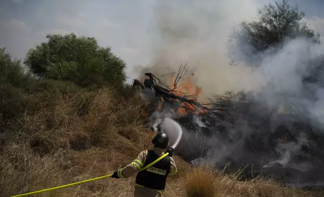 An Israeli firefighter works to extinguish a fire burning in an area, following an attack from Lebanon, near the Kibbutz Snir, northern Israel, Monday, Sept. 16, 2024. (AP Photo/Leo Correa)