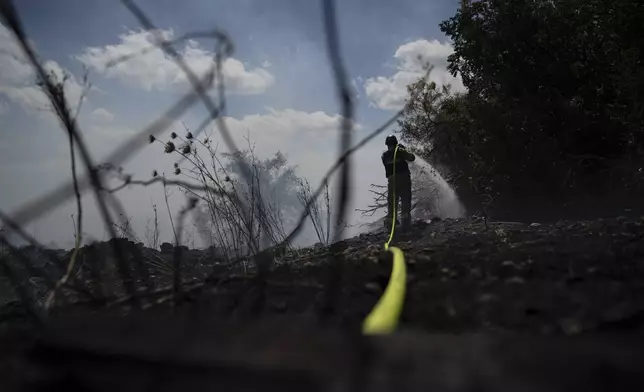 An Israeli firefighter works to extinguish a fire burning in an area, following an attack from Lebanon, near the Kibbutz Snir, northern Israel, Monday, Sept. 16, 2024. (AP Photo/Leo Correa)