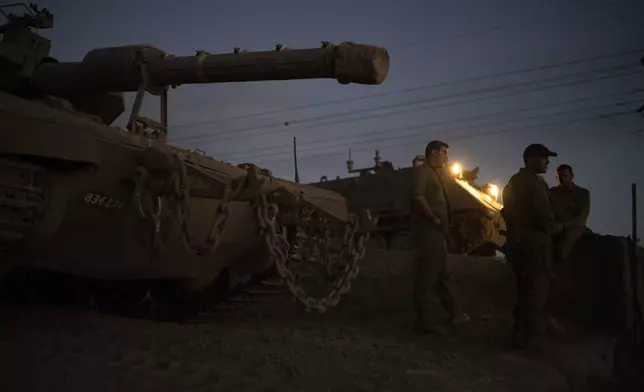 Israeli soldiers stand next to a tank on an area in the Israeli-annexed Golan Heights, Thursday, Sept. 19, 2024. (AP Photo/Leo Correa)