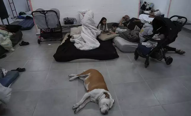 Israelis stay in a residential building bomb shelter to stay safe from rockets fired from Lebanon, in Kiryat Haim, northern Israel, on Tuesday, Sept. 24, 2024. (AP Photo/Baz Ratner)