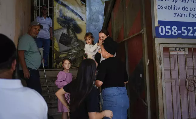 People take cover as a siren sounds a warning of incoming rockets fired from Lebanon, in Safed, northern Israel, Thursday, Sept. 26, 2024. (AP Photo/Ariel Schalit)